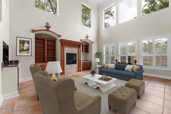 1821 Wind Ridge Ct, Fleming Island, FL 32003 - living room featuring a towering ceiling, healthy amount of natural light, a glass covered fireplace, baseboards, and light tile patterned floors