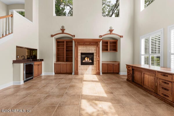 1821 Wind Ridge Ct, Fleming Island, FL 32003 - unfurnished living room featuring a high ceiling, wine cooler, a tiled fireplace, light tile patterned floors, and baseboards