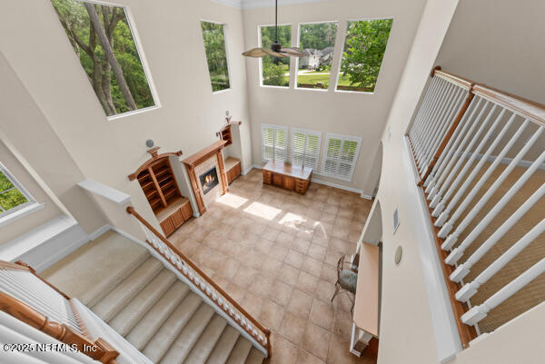 1821 Wind Ridge Ct, Fleming Island, FL 32003 - staircase featuring plenty of natural light, a towering ceiling, a lit fireplace, and baseboards
