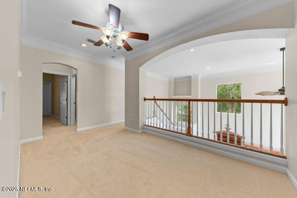 1821 Wind Ridge Ct, Fleming Island, FL 32003 - spare room featuring arched walkways, ceiling fan, ornamental molding, baseboards, and carpet flooring