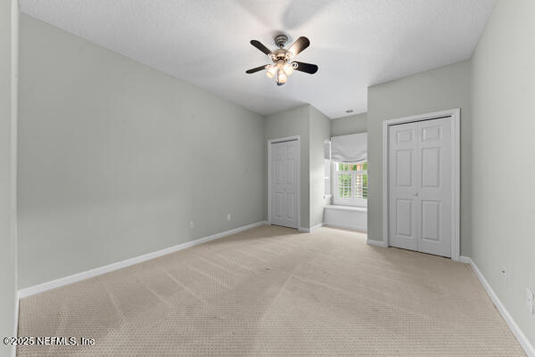 1821 Wind Ridge Ct, Fleming Island, FL 32003 - unfurnished bedroom with two closets, light carpet, and baseboards