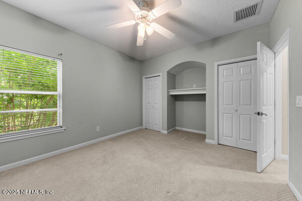 1821 Wind Ridge Ct, Fleming Island, FL 32003 - unfurnished bedroom with carpet floors, two closets, baseboards, and ceiling fan