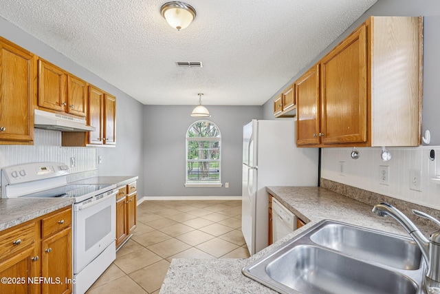 1645 Teaberry Dr, Middleburg, FL 32068 - kitchen featuring white appliances, under cabinet range hood, a textured ceiling, light tile patterned floors, and brown cabinetry