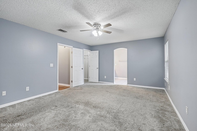 1645 Teaberry Dr, Middleburg, FL 32068 - unfurnished bedroom featuring arched walkways, carpet floors, a textured ceiling, a ceiling fan, and a walk in closet