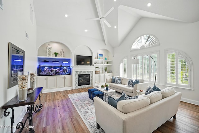 4427 Royal Tern Ct, Jacksonville Beach, FL 32250 - living room featuring plenty of natural light, a ceiling fan, a tiled fireplace, high vaulted ceiling, and wood finished floors