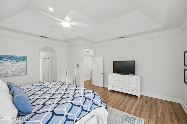 4427 Royal Tern Ct, Jacksonville Beach, FL 32250 - bedroom featuring wood finished floors, arched walkways, a tray ceiling, ceiling fan, and crown molding