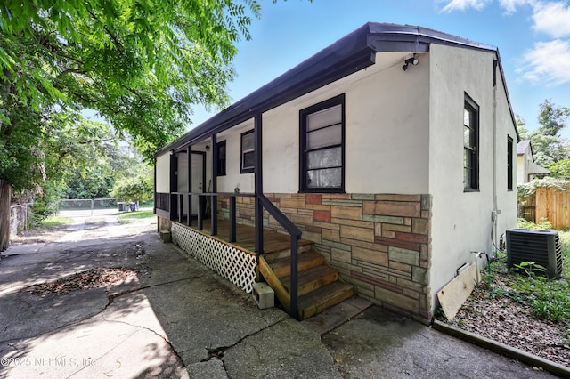 1176 Dancy St, Jacksonville, FL 32205 - view of home's exterior featuring central AC, stucco siding, stone siding, and a sunroom