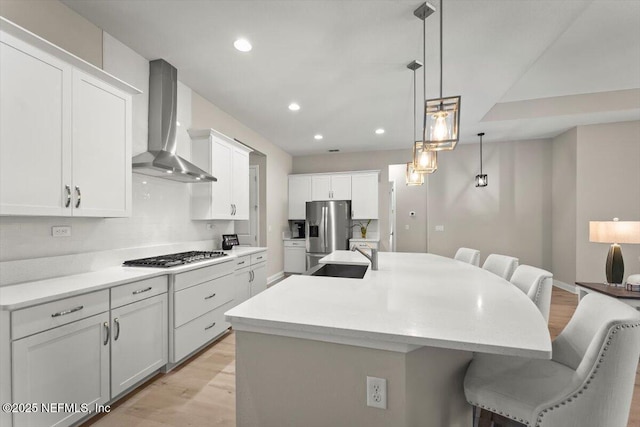 286 Holly Landing Way, Saint Augustine, FL 32092 - kitchen featuring wall chimney exhaust hood, appliances with stainless steel finishes, a breakfast bar area, light wood finished floors, and recessed lighting