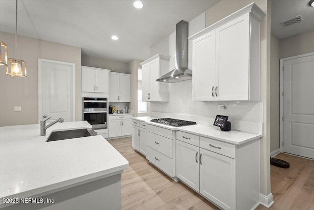 286 Holly Landing Way, Saint Augustine, FL 32092 - kitchen with wall chimney range hood, a sink, light wood-style floors, stainless steel appliances, and white cabinetry