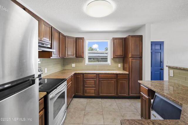 3121 Holly Berry Ln, Jacksonville, FL 32277 - kitchen featuring stainless steel appliances, under cabinet range hood, decorative backsplash, a textured ceiling, and light stone countertops