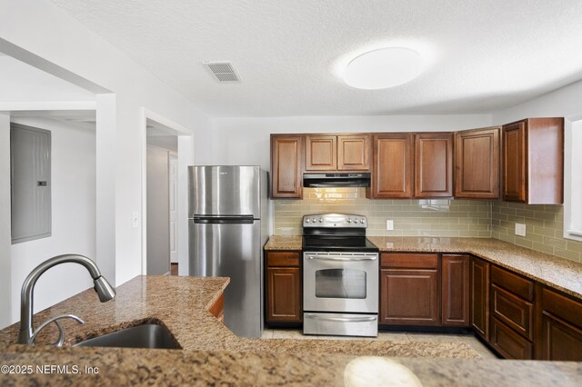 3121 Holly Berry Ln, Jacksonville, FL 32277 - kitchen featuring appliances with stainless steel finishes, extractor fan, light stone countertops, and decorative backsplash