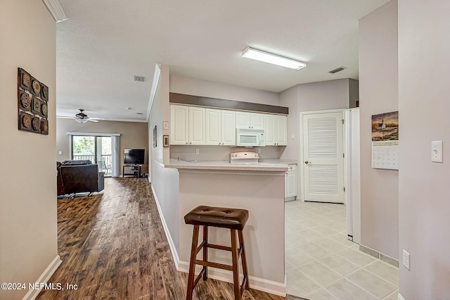 112 Laurel Wood Way Unit 202, Saint Augustine, FL 32086 - kitchen with white microwave, white cabinets, a breakfast bar area, light countertops, and a peninsula