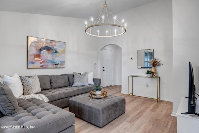 10961 Burnt Mill Rd Unit 1534, Jacksonville, FL 32256 - living room with arched walkways, a chandelier, light wood-style flooring, a towering ceiling, and baseboards