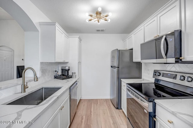 10961 Burnt Mill Rd Unit 1534, Jacksonville, FL 32256 - kitchen featuring appliances with stainless steel finishes, a sink, arched walkways, tasteful backsplash, and white cabinetry