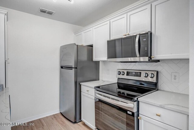 10961 Burnt Mill Rd Unit 1534, Jacksonville, FL 32256 - kitchen with stainless steel appliances, backsplash, light stone countertops, and white cabinets