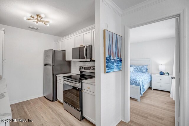 10961 Burnt Mill Rd Unit 1534, Jacksonville, FL 32256 - kitchen with appliances with stainless steel finishes, light wood finished floors, light countertops, white cabinets, and crown molding