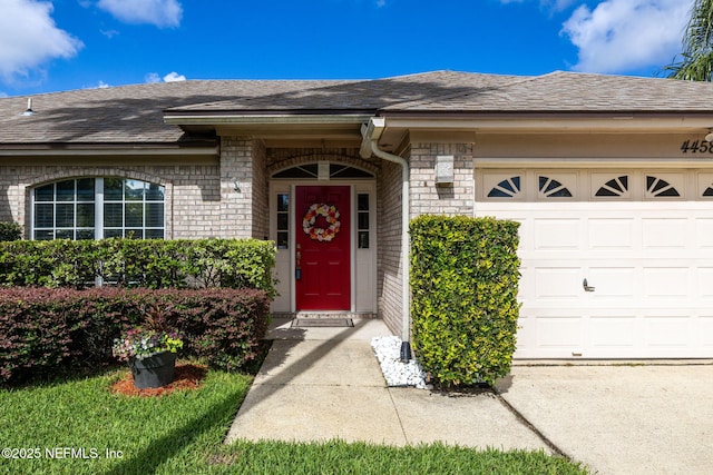4458 Deep River Way E, Jacksonville, FL 32224 - doorway to property featuring a garage, roof with shingles, and brick siding