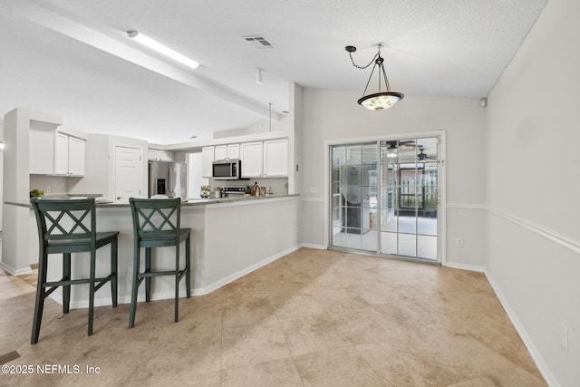 4458 Deep River Way E, Jacksonville, FL 32224 - kitchen featuring appliances with stainless steel finishes, lofted ceiling, white cabinetry, a peninsula, and pendant lighting