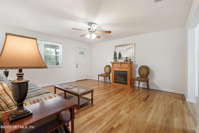 3130 Honeywood Dr, Jacksonville, FL 32277 - living area featuring light wood-style floors, ceiling fan, a glass covered fireplace, and baseboards