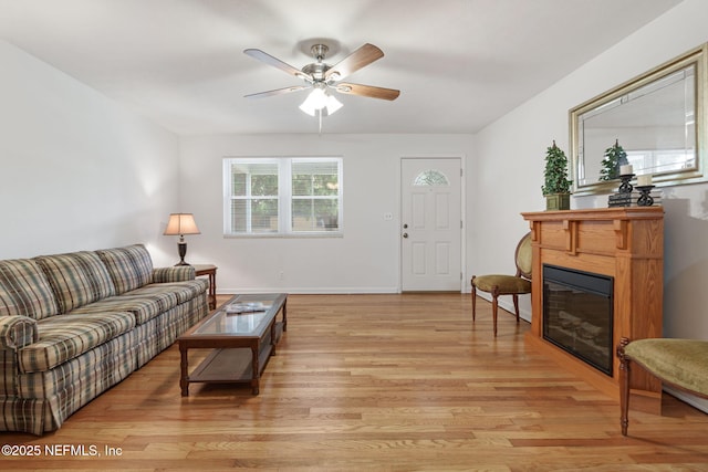 3130 Honeywood Dr, Jacksonville, FL 32277 - living room featuring light wood-type flooring, a glass covered fireplace, ceiling fan, and baseboards