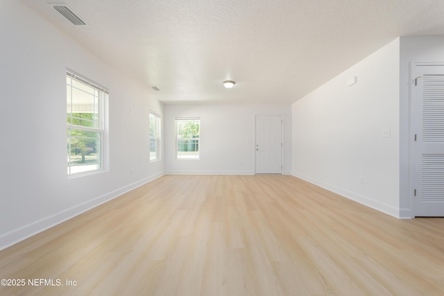 7127 Stetson St, Keystone Heights, FL 32656 - unfurnished living room featuring light wood-style flooring, plenty of natural light, baseboards, and a textured ceiling