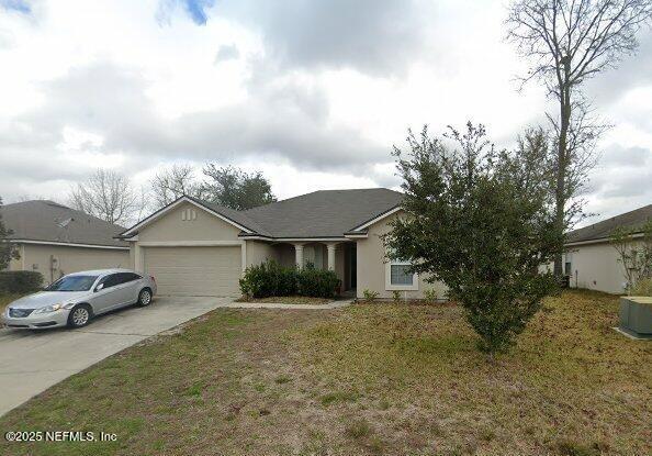 3251 Ginny Lake Dr, Middleburg, FL 32068 - view of front facade with a garage, driveway, a front lawn, and stucco siding