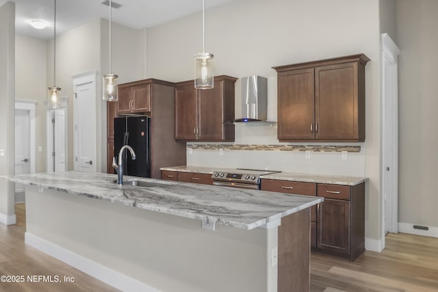 11 Woodstone Ln, Palm Coast, FL 32164 - kitchen featuring wall chimney exhaust hood, stainless steel electric range, freestanding refrigerator, decorative backsplash, and light wood finished floors
