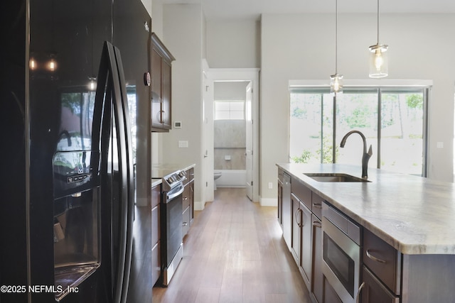 11 Woodstone Ln, Palm Coast, FL 32164 - kitchen featuring appliances with stainless steel finishes, a sink, light wood-style flooring, hanging light fixtures, and a kitchen island with sink
