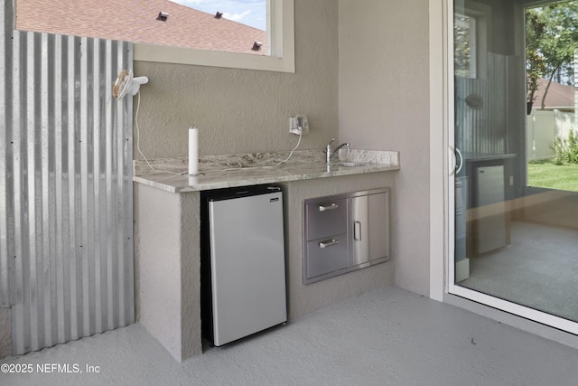 11 Woodstone Ln, Palm Coast, FL 32164 - indoor wet bar featuring freestanding refrigerator and a textured wall