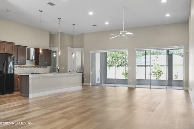 11 Woodstone Ln, Palm Coast, FL 32164 - kitchen featuring black fridge, open floor plan, a ceiling fan, light countertops, and decorative backsplash