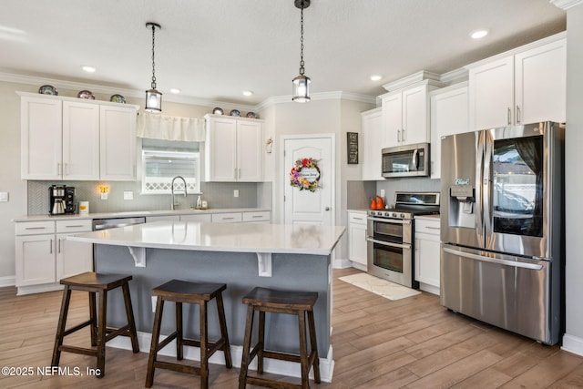 70 Creekmore Dr, Saint Augustine, FL 32092 - kitchen with stainless steel appliances, white cabinets, a breakfast bar, light countertops, and ornamental molding