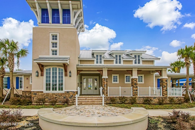 70 Creekmore Dr, Saint Augustine, FL 32092 - view of front facade with a standing seam roof, stone siding, french doors, stucco siding, and a metal roof