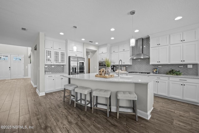 83 Tortola Way, Saint Johns, FL 32259 - kitchen with stainless steel appliances, wall chimney exhaust hood, tasteful backsplash, a center island with sink, and white cabinets