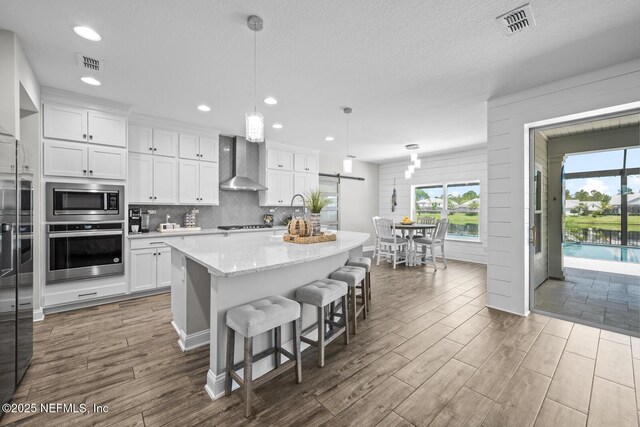 83 Tortola Way, Saint Johns, FL 32259 - kitchen featuring stainless steel appliances, wall chimney range hood, white cabinetry, dark wood-type flooring, and recessed lighting