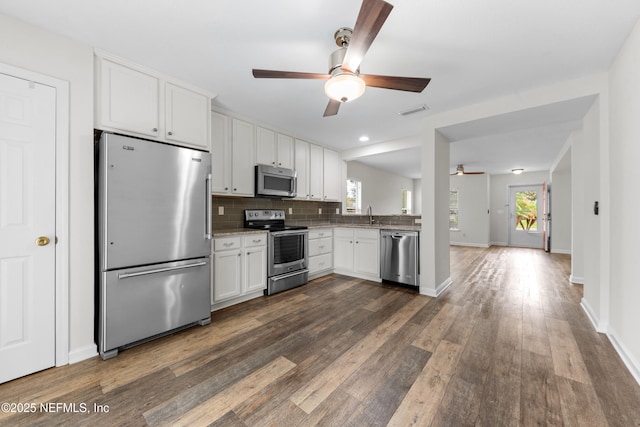 1101 Chokee Pl, Saint Augustine, FL 32092 - kitchen with stainless steel appliances, ceiling fan, dark wood-style flooring, backsplash, and white cabinetry