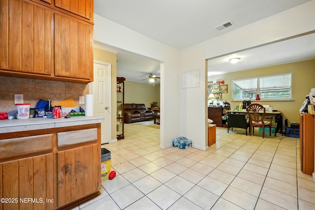 665 Grove Park Blvd, Jacksonville, FL 32216 - kitchen with light countertops, light tile patterned floors, ceiling fan, brown cabinetry, and backsplash