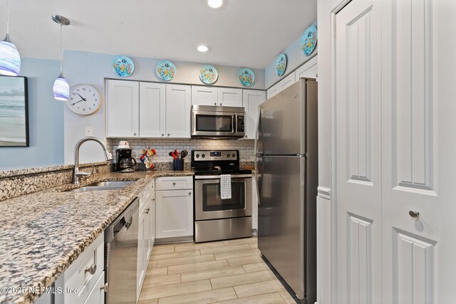 97 Village Las Palmas Cir, Saint Augustine, FL 32080 - kitchen featuring appliances with stainless steel finishes, a sink, white cabinets, light stone counters, and recessed lighting
