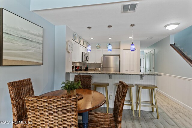 97 Village Las Palmas Cir, Saint Augustine, FL 32080 - dining room featuring light wood-style floors, a wainscoted wall, and stairway