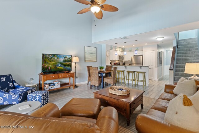97 Village Las Palmas Cir, Saint Augustine, FL 32080 - living area with light wood-type flooring, baseboards, stairs, a ceiling fan, and a towering ceiling