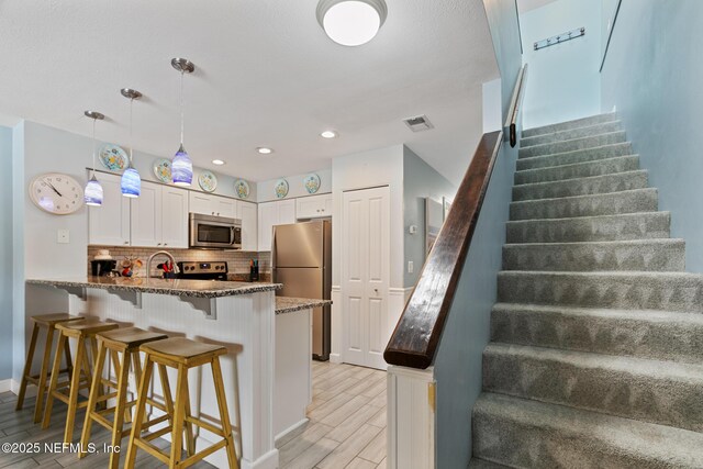 97 Village Las Palmas Cir, Saint Augustine, FL 32080 - kitchen featuring stainless steel appliances, a peninsula, dark stone counters, backsplash, and a breakfast bar