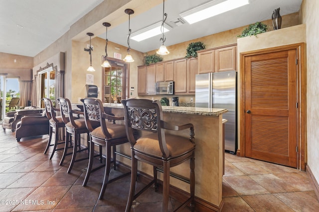 108 Laguna Villas Blvd Unit D22, Jacksonville Beach, FL 32250 - kitchen with appliances with stainless steel finishes, a kitchen bar, pendant lighting, light stone countertops, and baseboards