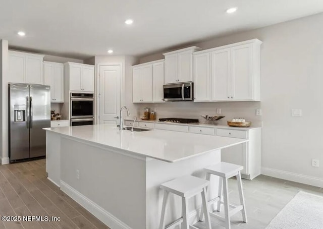 85 Otsego Ln, Saint Johns, FL 32092 - kitchen with stainless steel appliances, a sink, baseboards, white cabinetry, and a center island with sink