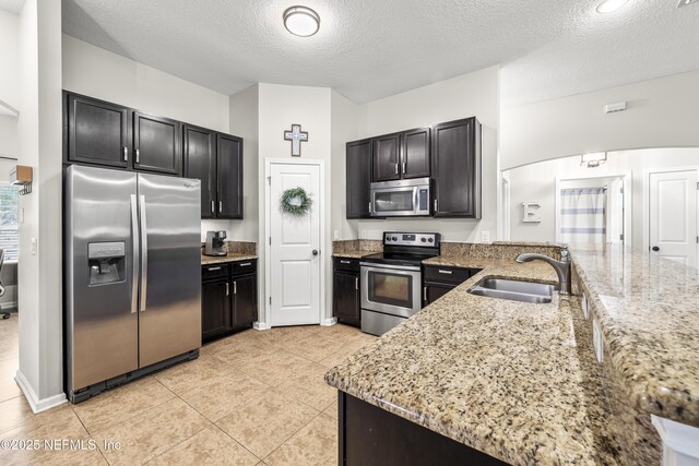 81014 Lockhaven Dr, Yulee, FL 32097 - kitchen featuring appliances with stainless steel finishes, a sink, light stone counters, a peninsula, and a textured ceiling