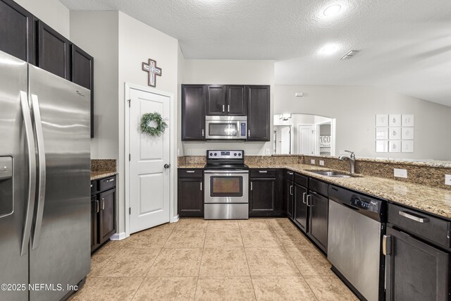 81014 Lockhaven Dr, Yulee, FL 32097 - kitchen with appliances with stainless steel finishes, a sink, light stone countertops, a textured ceiling, and light tile patterned floors