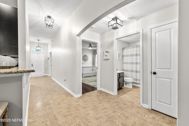 81014 Lockhaven Dr, Yulee, FL 32097 - hallway with light tile patterned floors, a textured ceiling, baseboards, and arched walkways