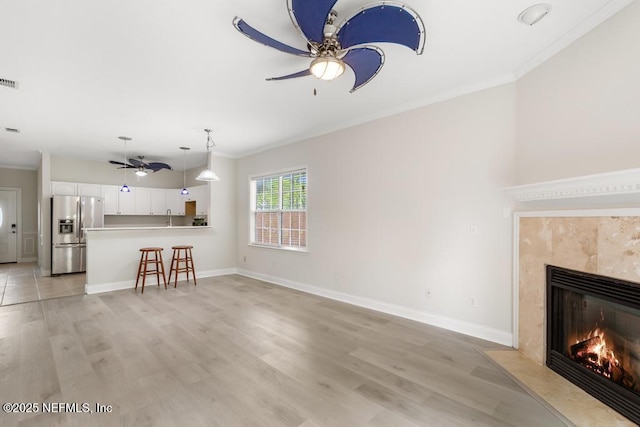 66 W 14th St, Atlantic Beach, FL 32233 - unfurnished living room with ceiling fan, ornamental molding, a high end fireplace, light wood finished floors, and baseboards