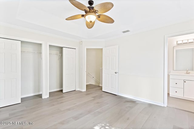 66 W 14th St, Atlantic Beach, FL 32233 - unfurnished bedroom featuring two closets, crown molding, light wood finished floors, a sink, and a ceiling fan