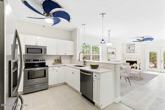 66 W 14th St, Atlantic Beach, FL 32233 - kitchen featuring appliances with stainless steel finishes, a sink, a ceiling fan, a peninsula, and a lit fireplace