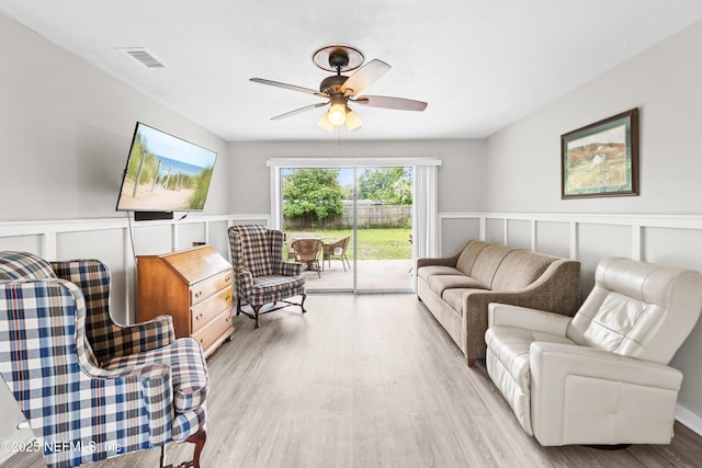 10836 Hawaii Dr S, Jacksonville, FL 32246 - living area featuring a ceiling fan, light wood-style floors, a wainscoted wall, and a decorative wall