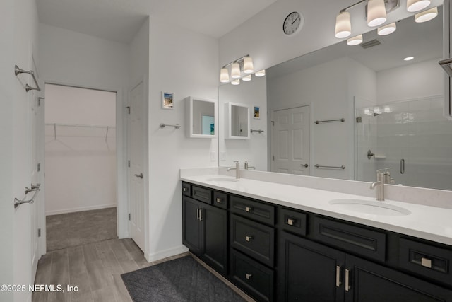 564 Jubilee Cir, Yulee, FL 32097 - bathroom featuring wood finished floors, double vanity, a shower stall, and a spacious closet